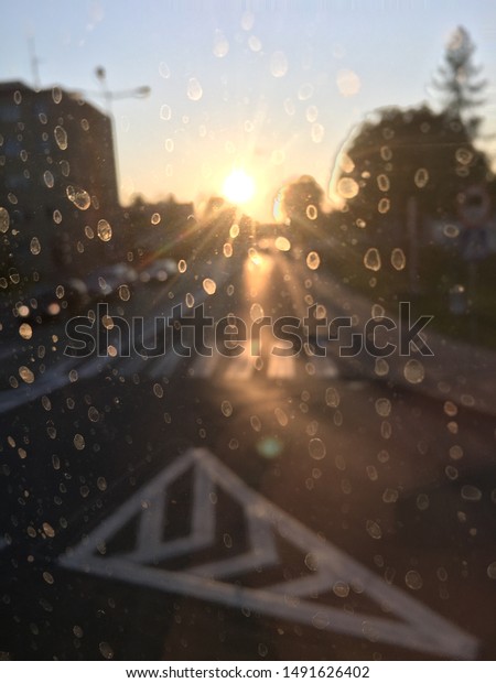 glass\
with traces of rain overlooking the road and\
sunset