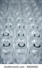 Glass transparent empty bottles in rows, cosmetics assembly line