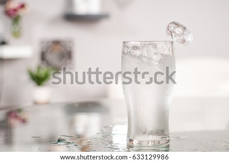 Glass of very cold water and ice on table