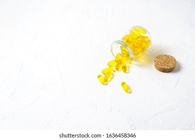 Glass Vial With Yellow Vitamins Tablets, Fish Oil, Omega Vitamin E. A Small Retro Jar With A Cork, Lies With Scattered Pills On A White Background. Flat Lay With A Copy Space.