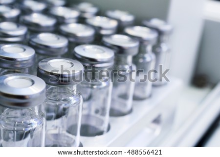 Glass vials for liquid samples. Laboratory equipment for dispensing fluid samples. Shallow depth of field.