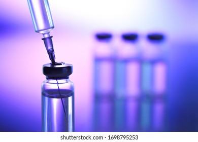  glass vials and a medical syringe with a coronavirus vaccine on a blue background