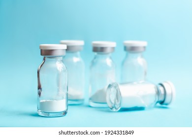 Glass vials with medicine in powder form on blue background, soft focus