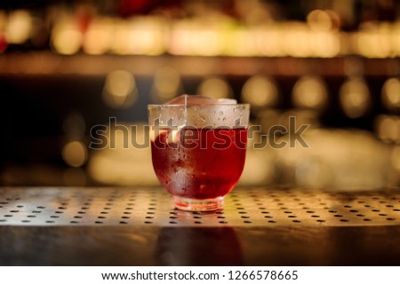 Glass of a Vieux Carre cocktail with big ice cube on the steel wooden bar counter on the blurred background [[stock_photo]] © 