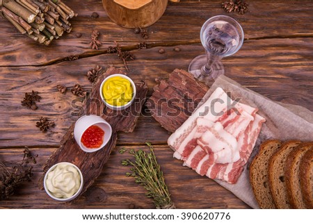 Glass of vodka, fat with bread on a dark wooden board
