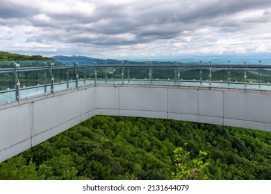 Glass walkway (observation deck) with transparent floor overlooking natural scenery of Sataplia Nature Reserve in Georgia. 