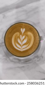 A glass of warm cappuccino with creamy foam in a clear glass. The cappuccino is made from high-quality Indonesian coffee beans. The smooth, velvety foam adds a luxurious texture.