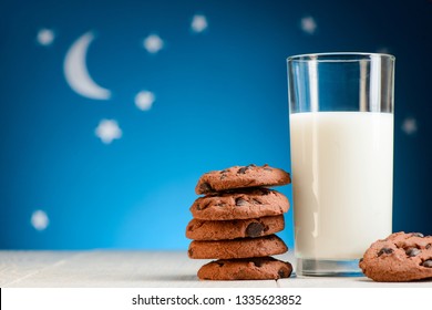 Glass Of Warm Milk And Cookies Before Bed. Blue Night Sky Background With Stars And Moon.