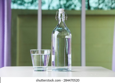 Glass Of Water With A Bottle On Table