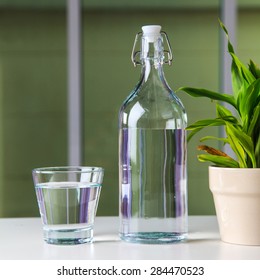 Glass Of Water With A Bottle On Table