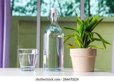 Glass Of Water With A Bottle On Table