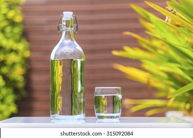 Glass Of Water With A Bottle On Table