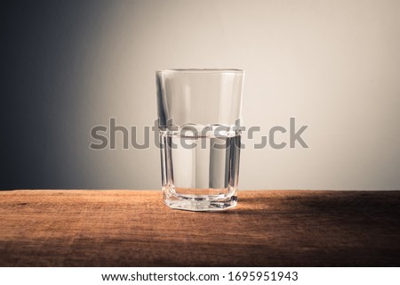 Glass of water with half full water on the table, concept of positive and negative thinking