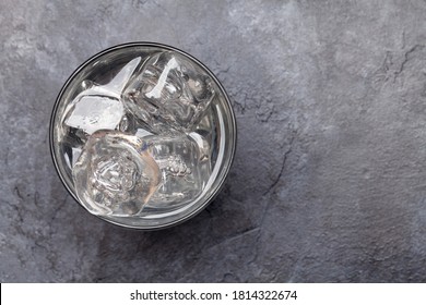 Glass of water with ice cubes on stone table. Top view flat lay with copy space
