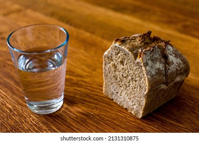 A Glass Of Water And A Loaf Of Bread On A Wooden Table. Fasting For Bread And Water To Strengthen The Spirit. Lent. Easter. Prison Food. Food For Poor.