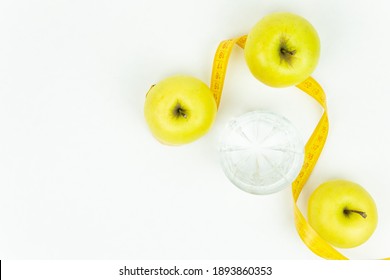 A glass of water and a measuring tape wrapped around three green apples as a symbol of diet. The concept of a healthy lifestyle, food and sports, on a white background. Top view with place for text or - Shutterstock ID 1893860353