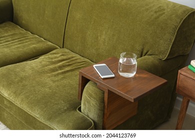 Glass Of Water With Mobile Phone On Armrest Table In Room