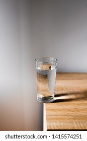 A Glass Of Water On The Edge Of A Table, Ready To Fall. 