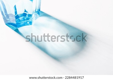 A Glass with Water and Sharp Shadows, Caustic Effect as Light Passes Through on Bright Background