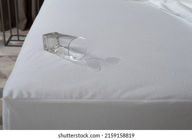 A Glass Of Water Spilled On The Bed. Spilled Water In Bed