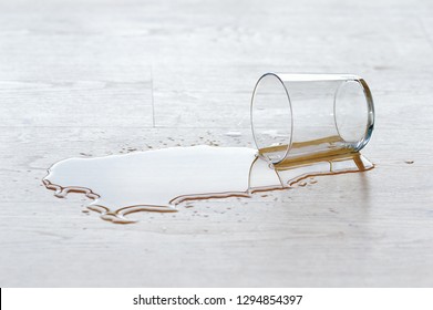 Glass Of Water Spilled On Wooden Floor