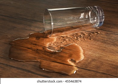Glass of water spilled on wooden background