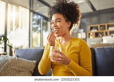 Glass, water and woman with medicine on sofa for health, self care and supplement at home. Relax, healthcare and happy african person with liquid drink and pill or tablet for wellness on couch - Powered by Shutterstock