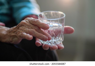 A Glass Of Water In The Wrinkled Hands Of An Elderly Woman, Grandmother Drinks Water, Health Care, The Benefits Of Drinking Water For An Old Man.
