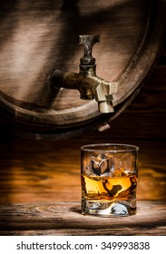 Glass Of Whiskey Or Brandy Ice Poured From An Old Oak Barrel