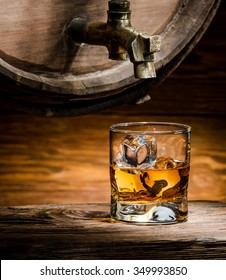 Glass Of Whiskey Or Brandy Ice Poured From An Old Oak Barrel