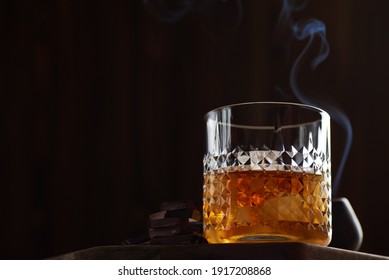 Glass of whiskey with chocolate in a smoke bar. Photo with copy space and selective focus.