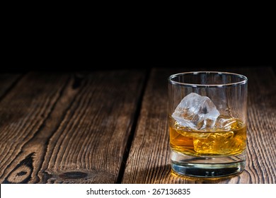 Glass with Whiskey (close-up shot) on rustic wooden background