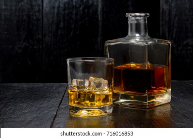 Glass Of Whiskey With A Decanter On A Black Wooden Background