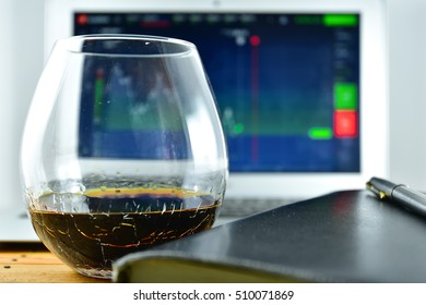 A Glass Of Whiskey In Front Of A Laptop With A Stock Ticker On The Screen