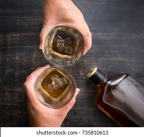 Glass Of Whiskey In Hand And Whiskey Bottle On Wooden Table,top View