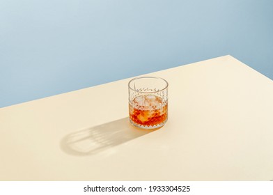Glass with Whiskey and Ice Cube on Table on Blue Background. Modern Isometric Style. Creative Concept
