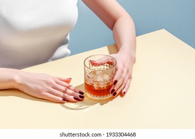 Glass With Whiskey And Ice Cube In Woman Hands On Table On Blue Background. Modern Isometric Style. Creative Concept