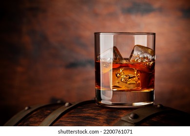 Glass Of Whiskey With Ice Cubes On The Old Barrel. With Copy Space On Wooden Background