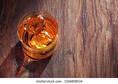 Glass Of Whiskey With Ice On Wooden Bar Table. Overhead View.