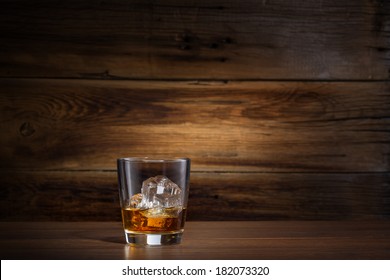 glass of whiskey with ice on a wooden background