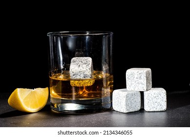 glass with whiskey and lemon on a dark background. Whiskey chilling stones on a glass table. Copy space.