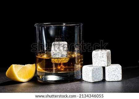 glass with whiskey and lemon on a dark background. Whiskey chilling stones on a glass table. Copy space.