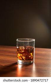 A Glass Of Whiskey On Ice On Wood Table