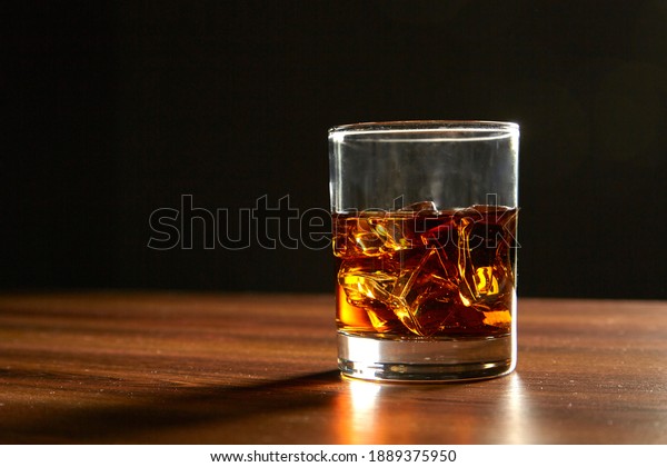 A Glass of whiskey\
on ice on wood table
