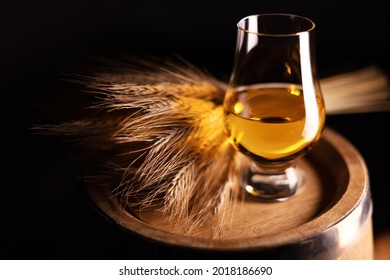 Ein Glas Whiskey auf alten Eichenfass mit einem Haufen Roggen. Traditionelles Alkoholdestillationskonzept