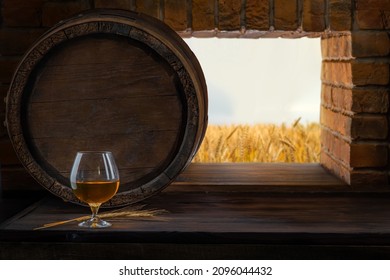 Glass with whiskey, spikelets of wheat, brandy on a vintage background of a rustic oaken barrel. Alcoholic beverage. Still life in the old style.