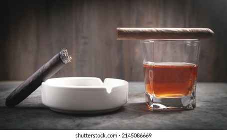 Glass of whisky, ashtray and cigar on the table.