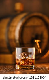 Glass Of Whisky With Ice With Barrel On Background (soft Focus Photo With Shallow Deph Of Field)