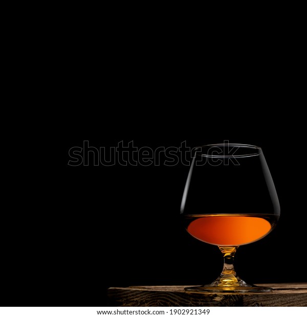 a\
glass of whisky with wooden box on black\
background