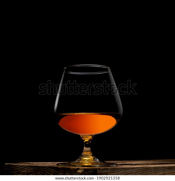 a\
glass of whisky with wooden box on black\
background